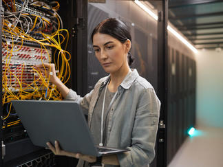 Technikerin überprüft ein Netzwerk mit ihrem Laptop im Serverraum